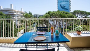 A balcony with a table set for two, overlooking a cityscape with modern buildings and a distinctive whale mural on one building. - le ponant by Interhome (Saint Laurent du Var)