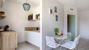 A modern kitchen with a microwave, sink, and wooden countertop. There is a dining area with a glass table and white chairs. - le ponant by Interhome (Saint Laurent du Var)