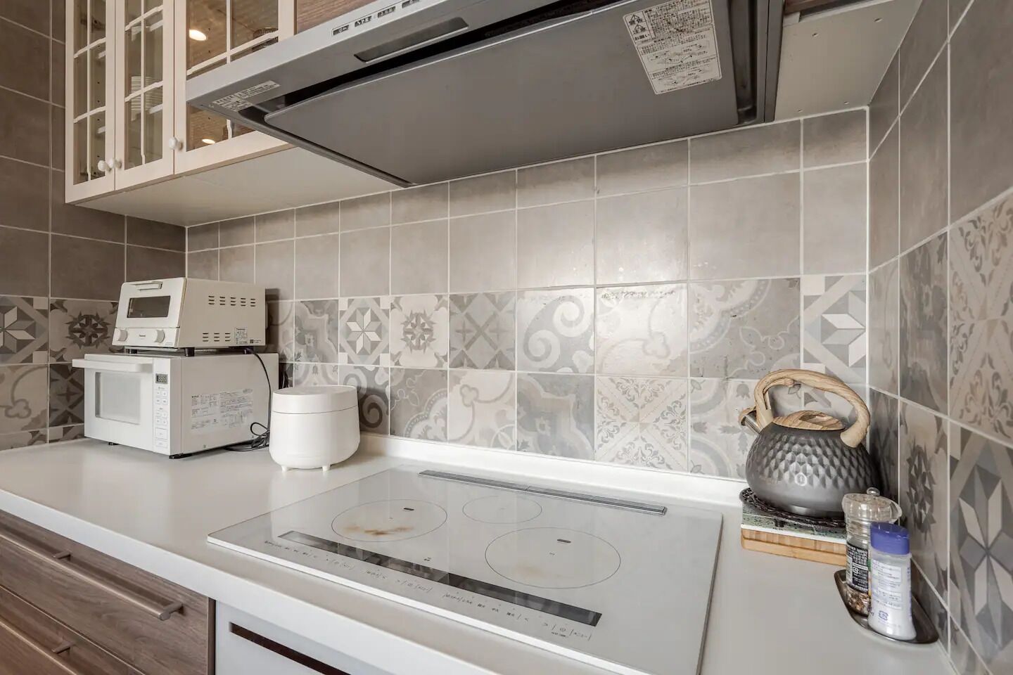 A modern kitchen with a built-in microwave, a kettle, and a stovetop.