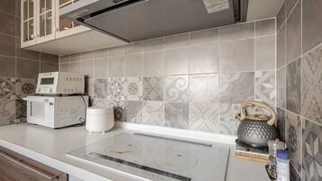 A modern kitchen with a built-in microwave, a kettle, and a stovetop.