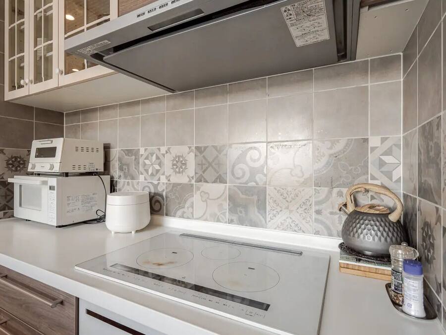 A modern kitchen with a built-in microwave, a kettle, and a stovetop.