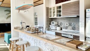 Una cocina moderna con encimera de mármol, armarios blancos y microondas integrado.