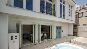 Una casa de dos pisos con un patio, un jacuzzi y un comedor visible a través de puertas abiertas.
