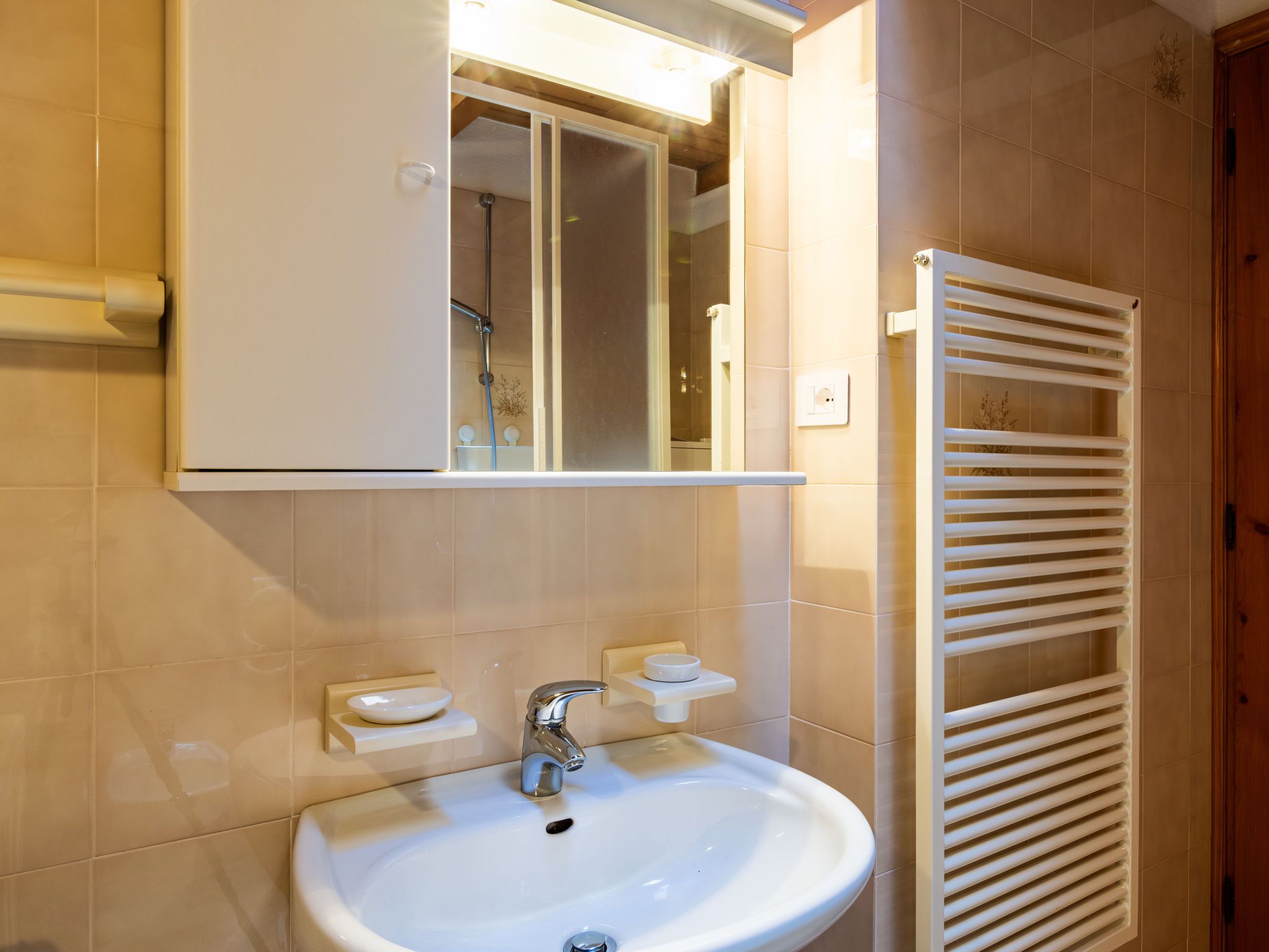 A bathroom with a white sink, a mirror above it, and a towel rack to the right.