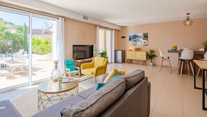A spacious living area with a sofa, chairs, a TV, and a dining area with a table and chairs. - Villa Julia by Interhome (Les Issambres)