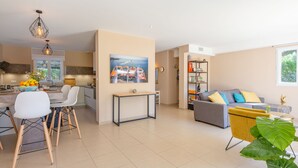 A modern living room with a grey sofa, a yellow armchair, and a dining area with a white table and chairs. - Villa Julia by Interhome (Les Issambres)