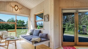 A cozy room with a wooden interior, a sofa, a rocking chair, and a large window offering a view of the outdoors. - "Gligorij" - 450m from the sea by Interhome (Sæby)