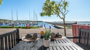 Una mesa de madera al aire libre con vista a un puerto deportivo y barcos.