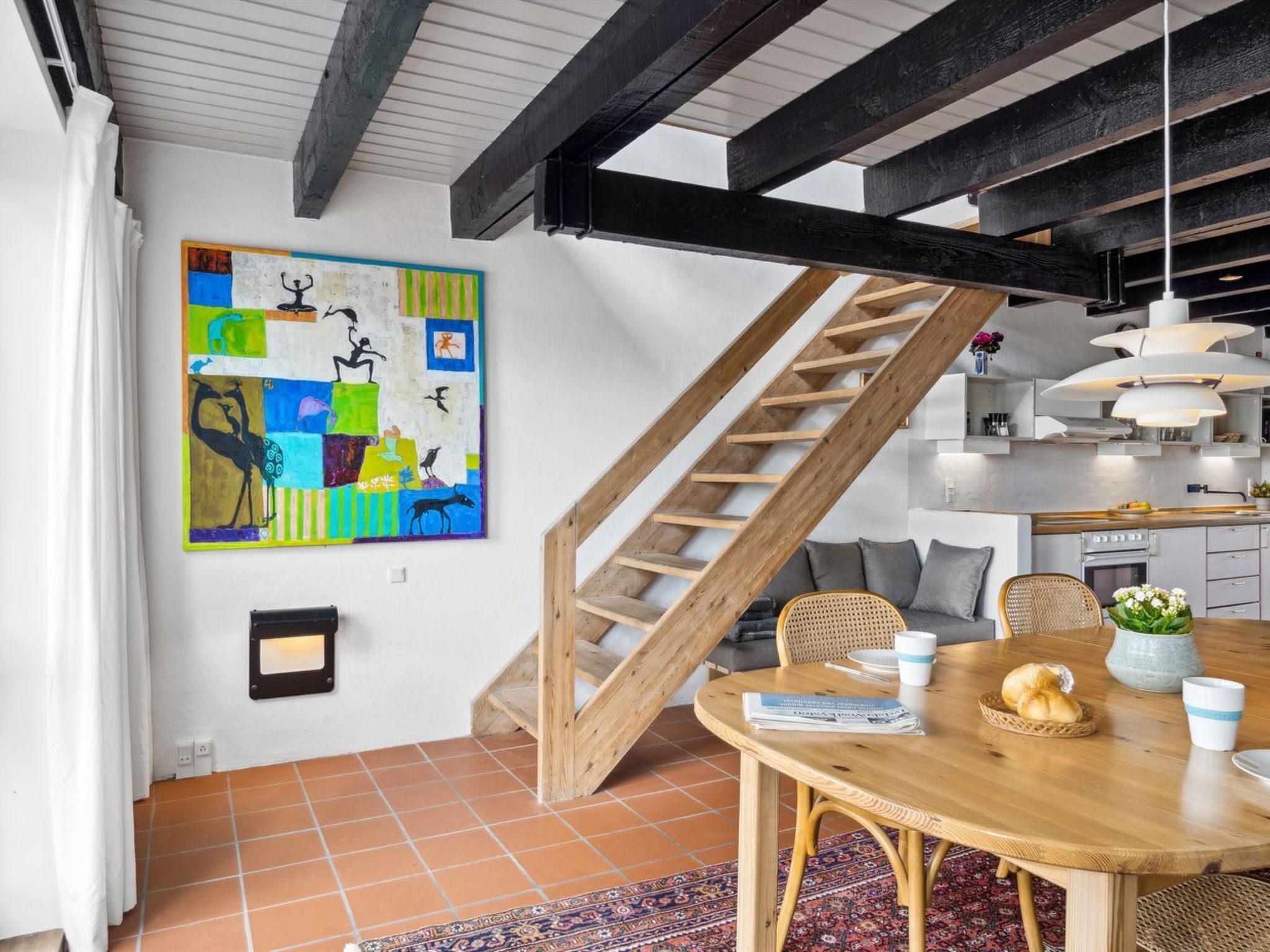 Un'area pranzo con un tavolo in legno, sedie e un quadro astratto dai colori vivaci appeso al muro.