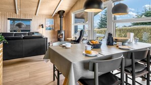 Een moderne keuken met een houten plafond, een centraal geplaatst fornuis en een eethoek met een tafel gedekt voor twee personen.