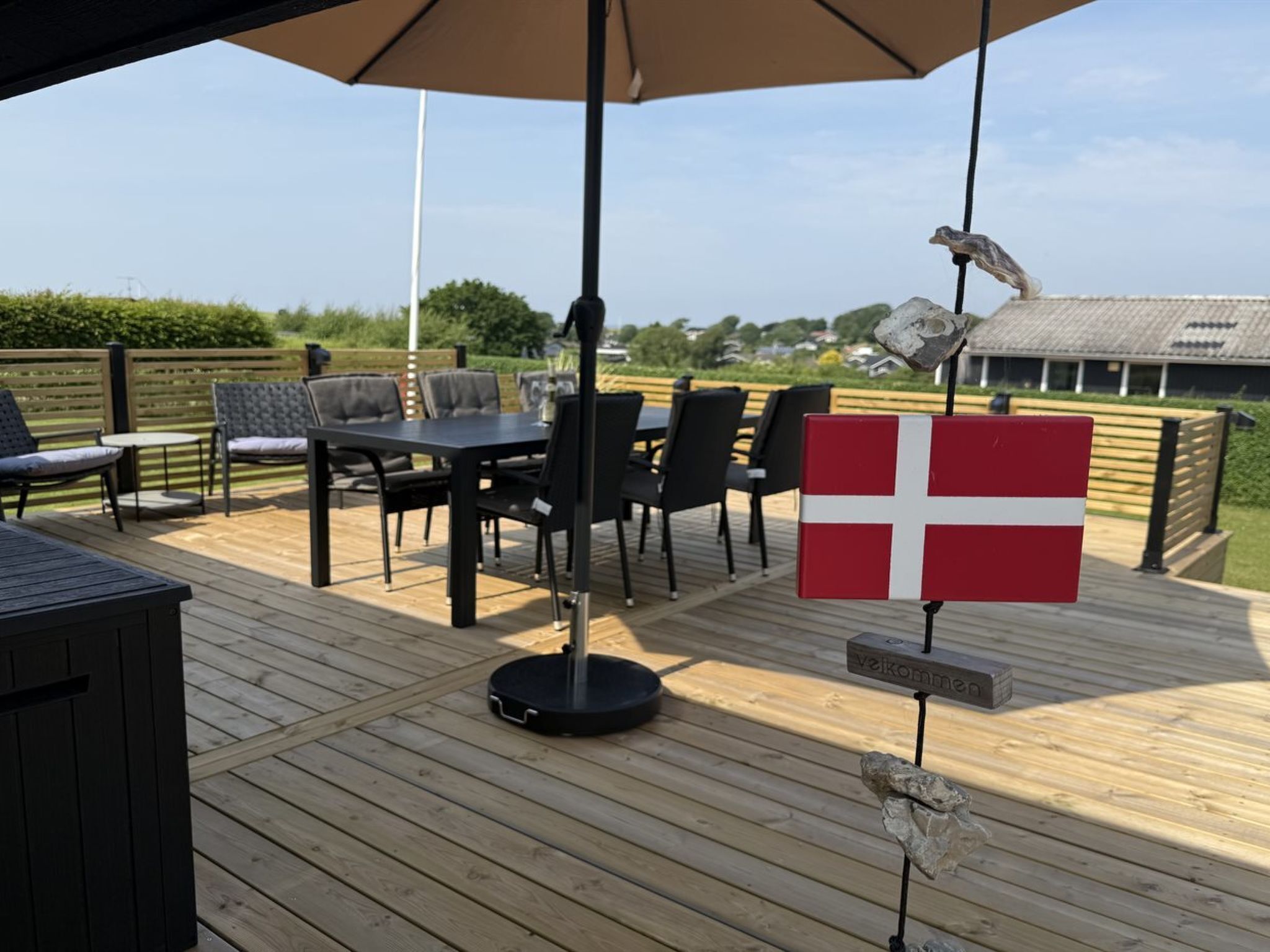 A wooden deck with a table and chairs, a flag, and a sign.