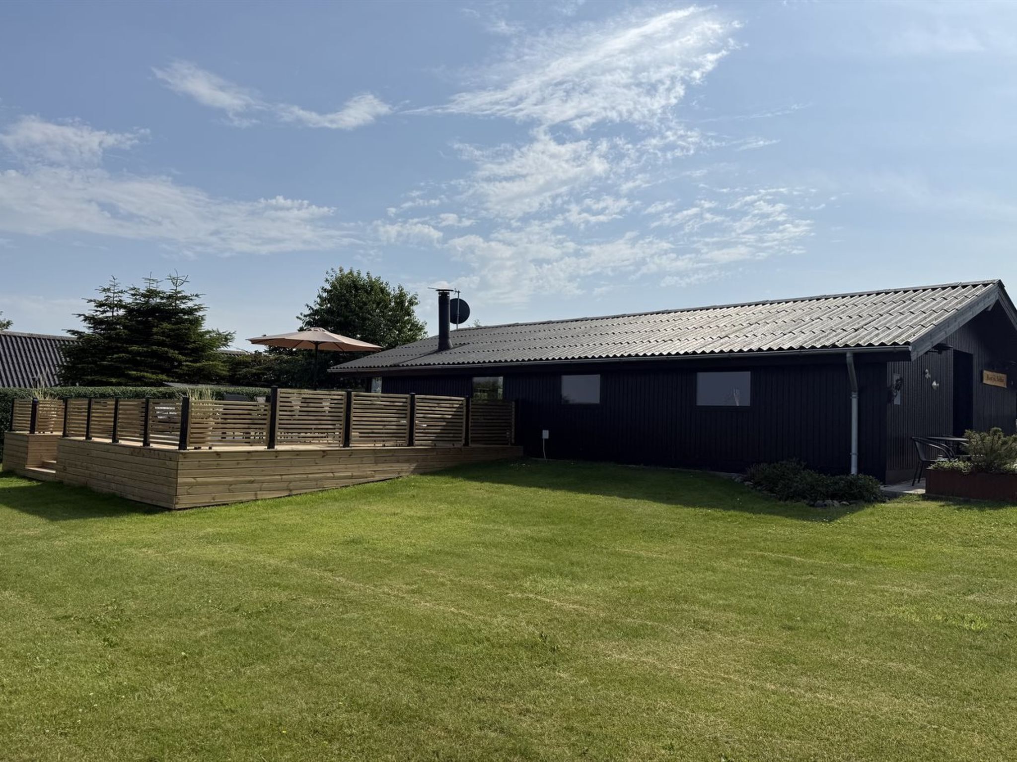 A building with a metal roof, a fenced area, and a grassy lawn.