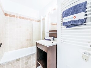 Ein Badezimmer mit einer Badewanne, einem Waschbecken mit Handtuchspender und einem Spiegel.
