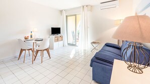A modern living room with a blue sofa, a dining table with chairs, a TV on a cabinet, and a lamp. - Caesar Domus by Interhome (Gassin)