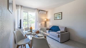 A modern living room with a dining area, a sofa, and a table set for breakfast.