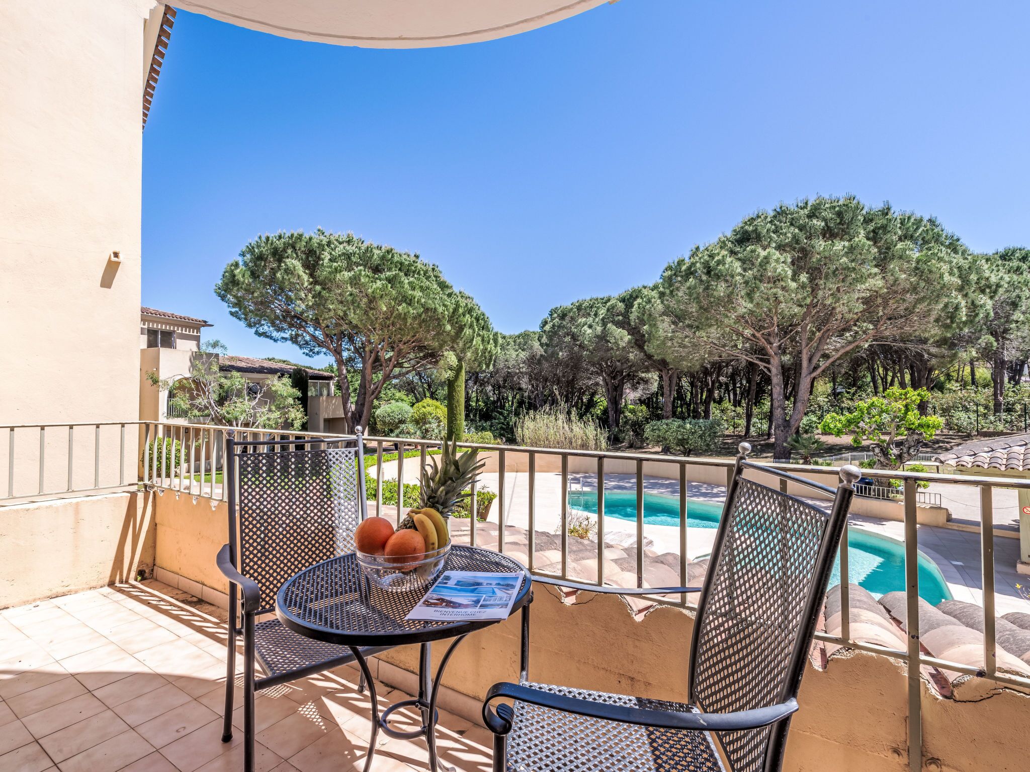A balcony with a table, chairs, and a fruit bowl.