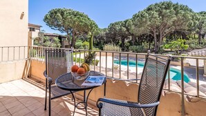 A balcony with a table, chairs, and a fruit bowl.