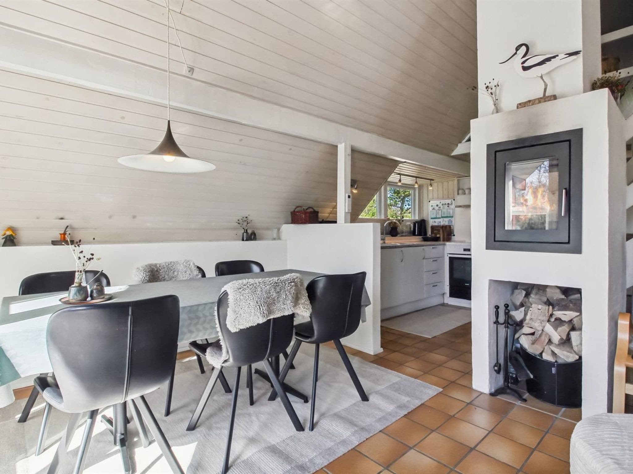 Une cuisine moderne avec un coin repas, un plafond en bois et une cheminée.