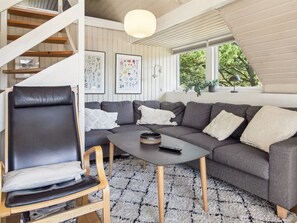 Una sala moderna con un sofá modular, un sillón de cuero, una mesa de centro y una escalera.