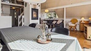 Un interior moderno con una mesa de comedor, sillas, una chimenea y una escalera.