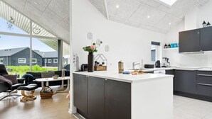A modern kitchen with a central island, dark cabinetry, and a large window overlooking a residential area.