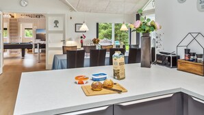 A modern kitchen with a large island, dining area, and a pool table.