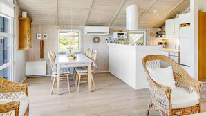 Un'ampia cucina con isola centrale, pavimento in legno e sedie in vimini.