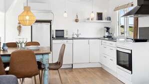 Eine moderne Küche mit weißen Schränken, einem Holztisch und einer Pendelleuchte.