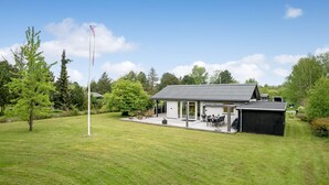 A modern house with a covered patio, a flagpole, and a well-maintained lawn.