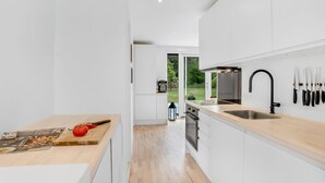 A modern kitchen with white cabinetry, a wooden countertop, and a black faucet.
