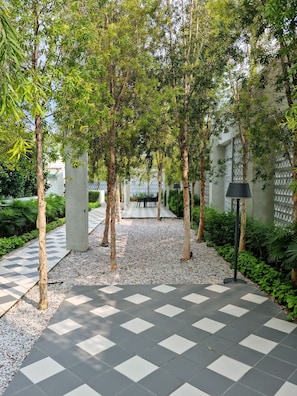 A pathway lined with trees and a checkered floor, leading to a covered seating area. - Una Residence By Maya (Kuala Lumpur)