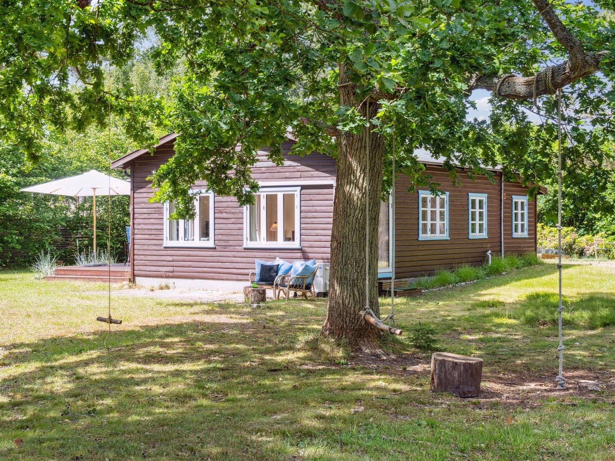 A rustic wooden cabin with a porch, a swing, and a small table.