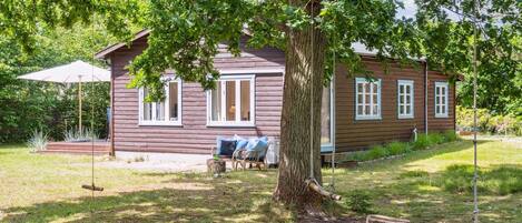 A rustic wooden cabin with a porch, a swing, and a small table.