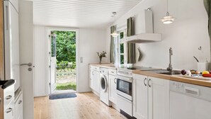 A modern kitchen with white cabinets, a wooden countertop, a built-in oven, and a washing machine. - "Heidl" - 1.3km to the fjord by Interhome (Rørvig)
