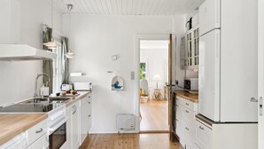 A modern kitchen with white cabinetry, a wooden countertop, and a view into the dining area. - "Heidl" - 1.3km to the fjord by Interhome (Rørvig)