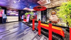 A modern interior with a Buddha statue, red pillars, and a digital screen. - Hotel Lotus Umeda - Adult Only　 (Osaka)