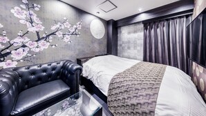 A modern bedroom with a large bed, a leather sofa, and a wall mural of cherry blossoms. - Hotel Lotus Umeda - Adult Only　 (Osaka)