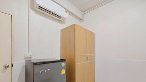 Une pièce de taille modeste, dotée d’un réfrigérateur, d’une armoire en bois et d’un sol carrelé de couleur blanche.