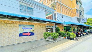 Un immeuble avec une enseigne indiquant « ZE RESIDENCE », un auvent bleu et une rangée de motos garées.