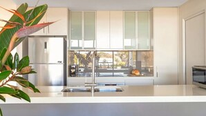 Una cocina moderna con un refrigerador de acero inoxidable, un lavamanos doble y una ventana con vista a la calle.