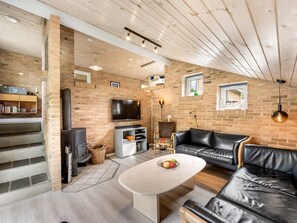 A modern living room with a fireplace, leather sofa, TV, and a dining area with a table.