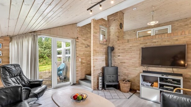 Un salon moderne avec une cheminée en pierre, un téléviseur à écran plat, des canapés en cuir et une porte vitrée donnant sur une terrasse.