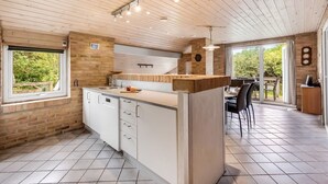 Une cuisine moderne avec un plafond en bois, un mur en briques et une grande fenêtre.