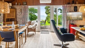 A cozy cabin interior with a wooden ceiling, a dining area, a comfortable chair, a television, and a view of the outdoors. - "Uschi" - 86m from the sea by Interhome (Kalundborg)