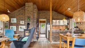 A cozy interior with a brick fireplace, wooden ceiling, and a dining area with blue chairs. - "Uschi" - 86m from the sea by Interhome (Kalundborg)