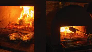 Horno de ladrillo para pizzas con fuego encendido en su interior.