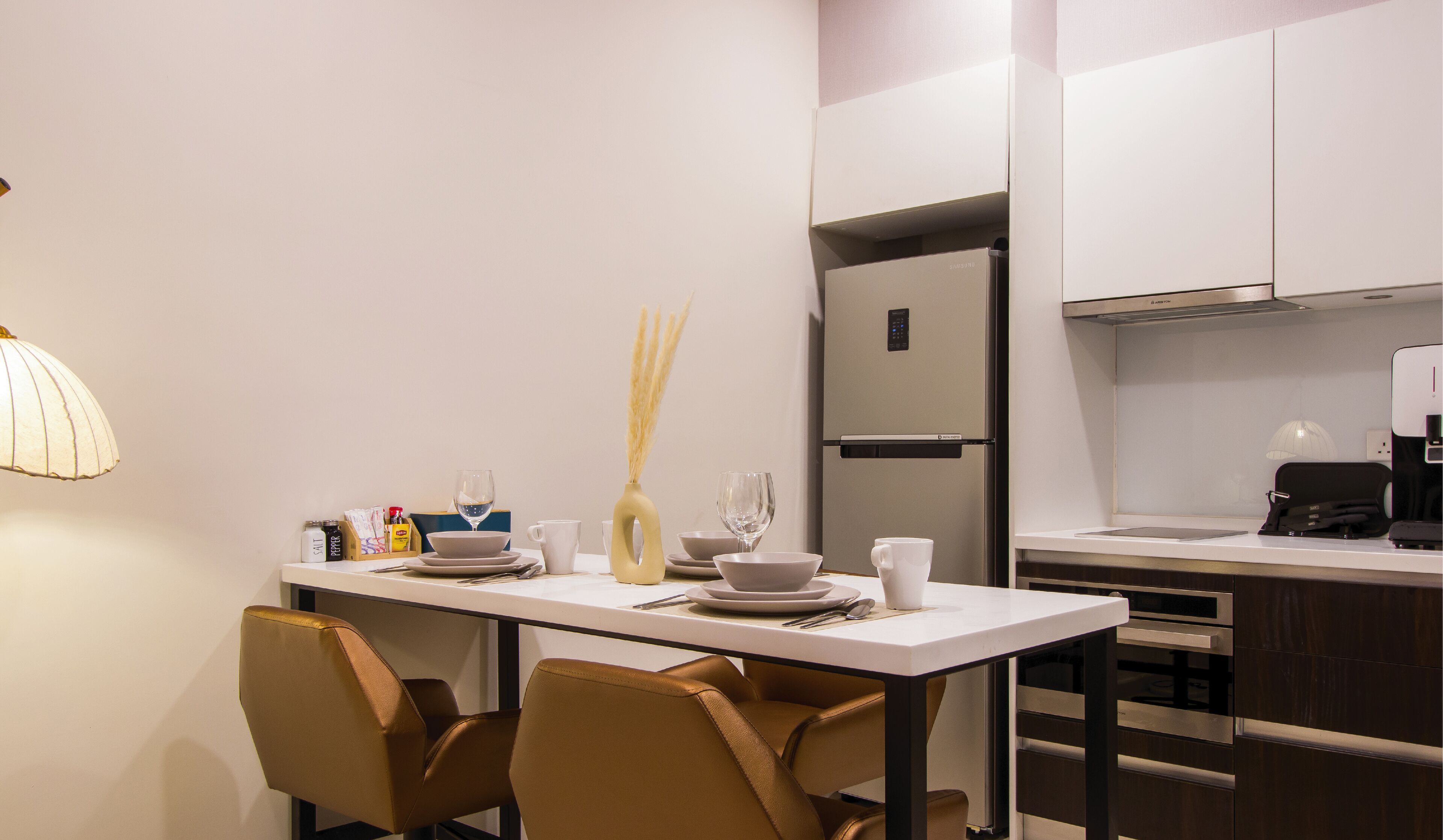 A modern kitchen with a dining area, featuring a white table, brown chairs, and a built-in refrigerator.
