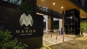 Een hotelentree met een modern design, met een opvallend logo en een glazen gevel.