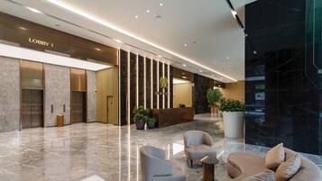 A modern lobby with marble flooring, seating areas, and a reception desk.