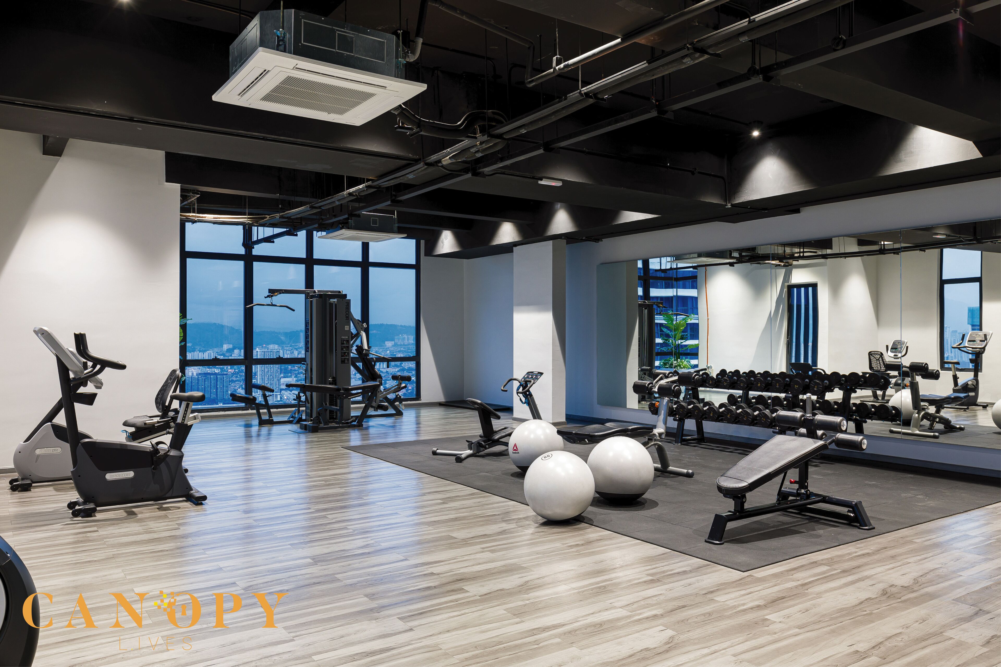A modern gym with various exercise equipment, large windows, and a city view.